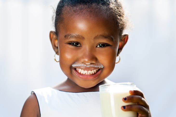 Little girl with milk moustache, smiling.