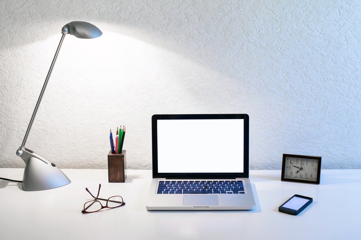 Tidy desk with open laptop, glasses.