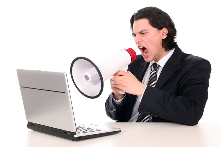 Man shouting through megaphone at computer.