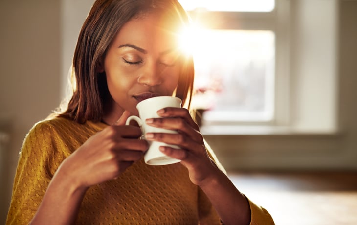 A black woman enjoys coffee as the morning sun rises
