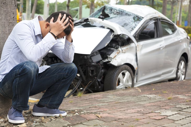 Upset man by smashed car.