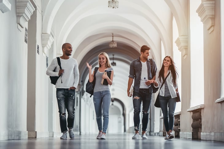 Students walk under outdoor archway.