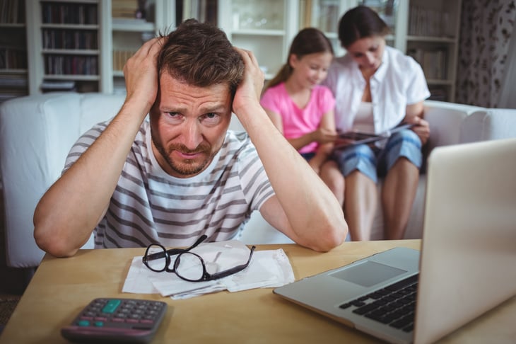 Worried man sitting at table with bills
