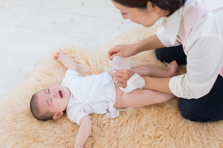 A mother changes a baby's diaper