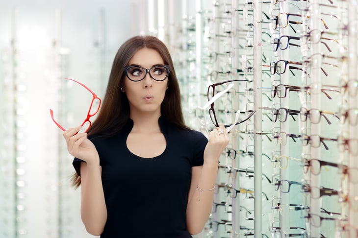A woman holds eyeglasses frames in a store