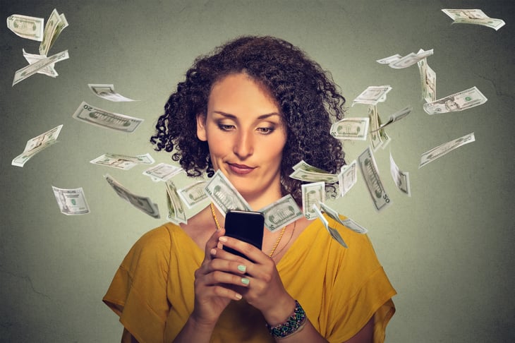 Woman watching money fly out of her phone.