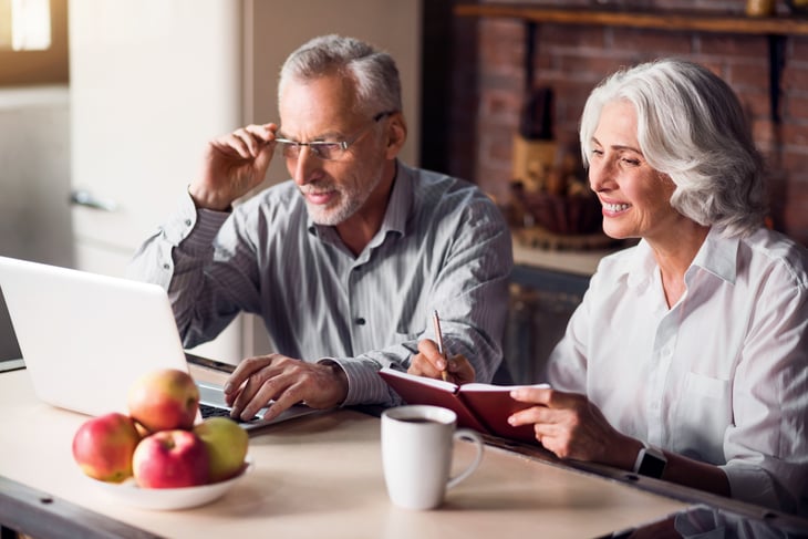 Older couple looking at computer, papers.