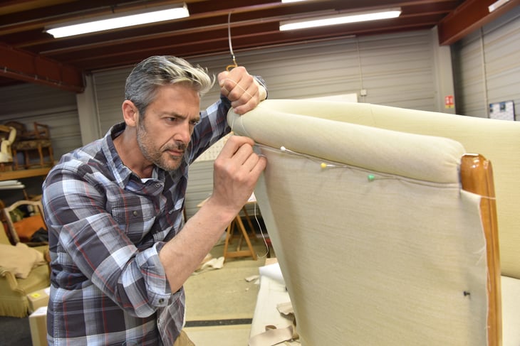 Man reupholstering a chair.