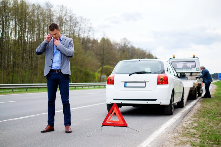 Man with car getting towed on the roadside