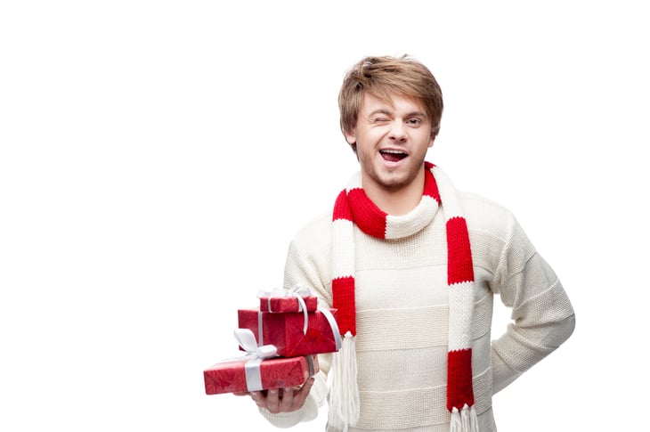 Man holding Christmas gift, winking.