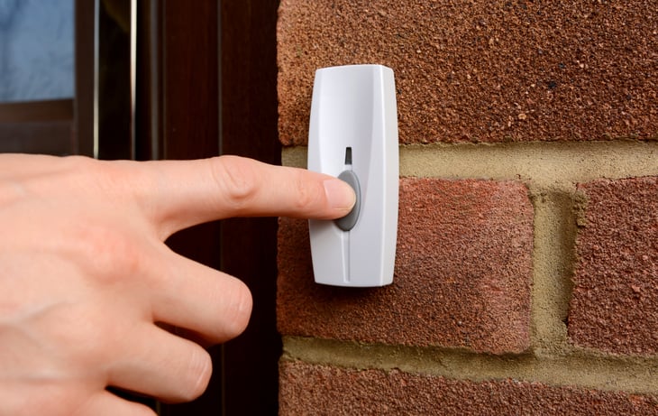 A finger pushing a doorbell