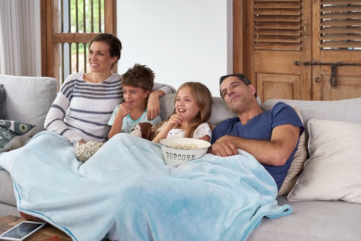 Family lounges on the couch and enjoys snacks
