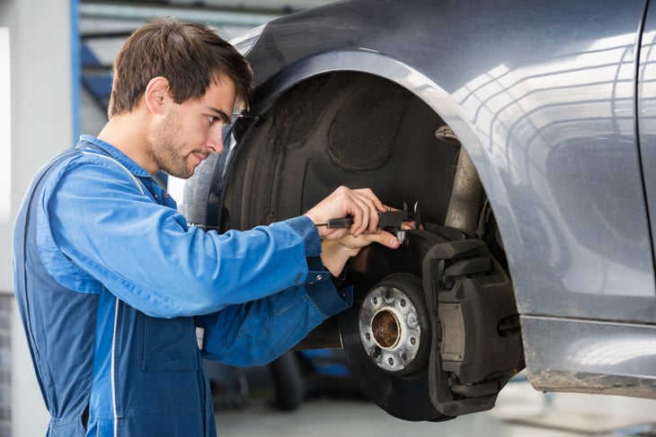 A mechanic inspect a car's brakes