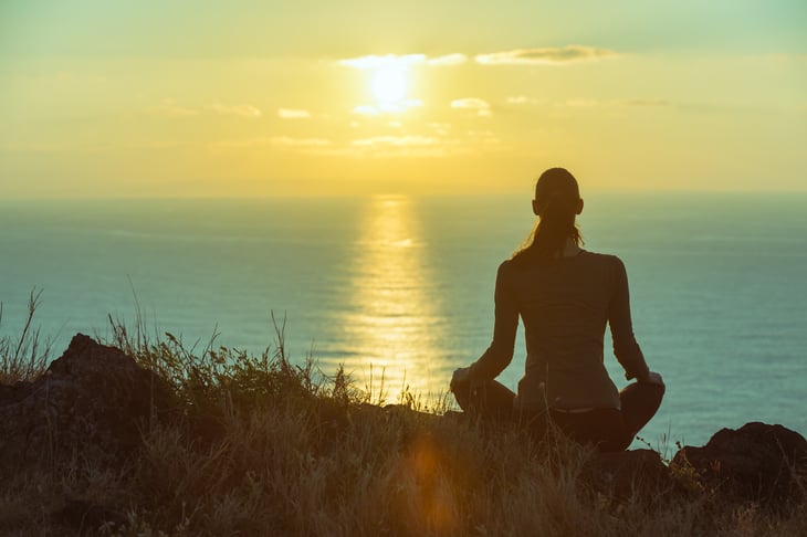 Woman meditating outdoors by the ocean