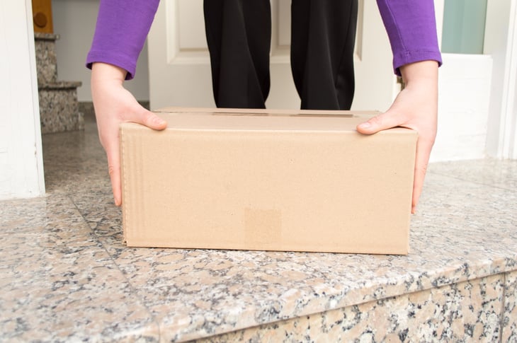 A person picks up a package from their front porch