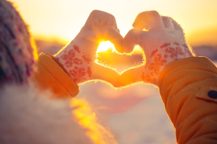 Hands making a heart shape at sunset
