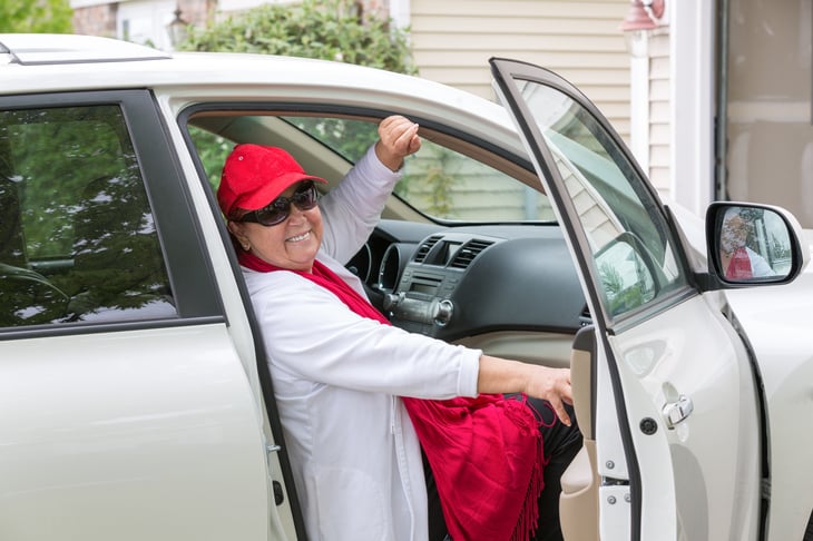 An older woman gets in the passenger seat of a minivan