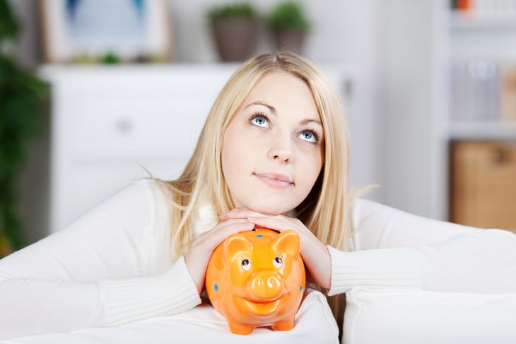 Thinking woman holding orange piggy bank