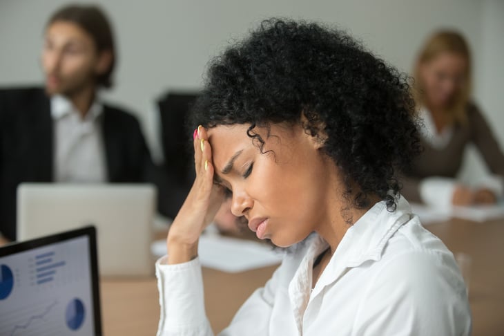 Woman at computer holding her head.