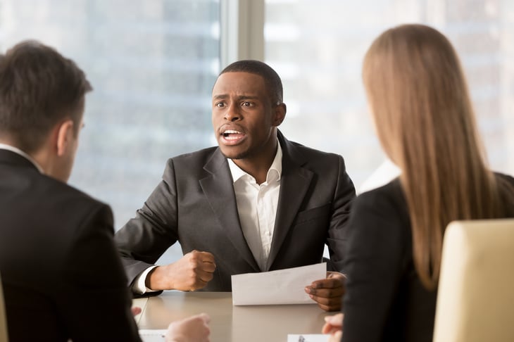 Angry businessman lashing out in a meeting.