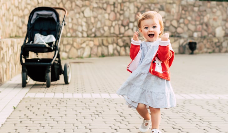 A toddler walks near a stroller