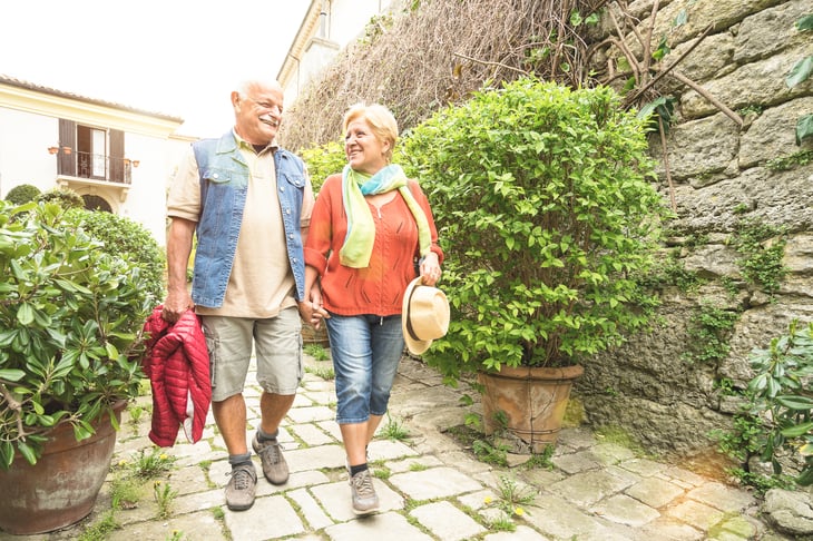Older couple walking cobblestones in Italy.