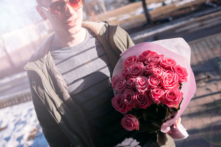 Young man with bouquet of pink roses.