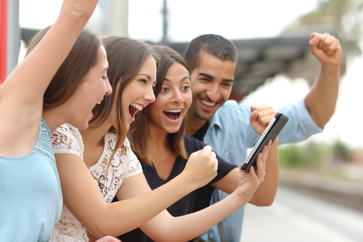 Four friends cheering at cellphone