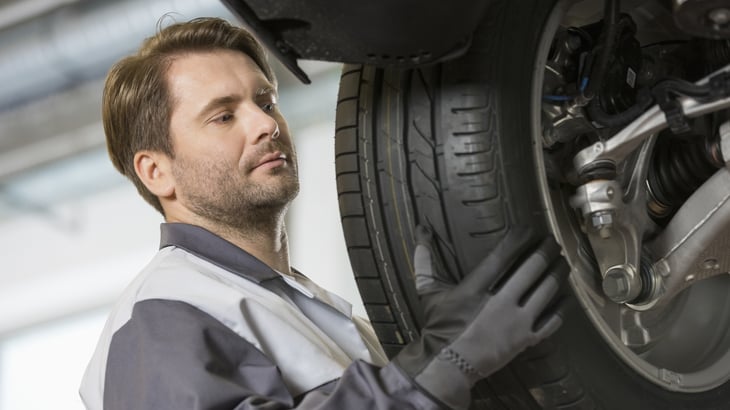 Man putting tire on car.