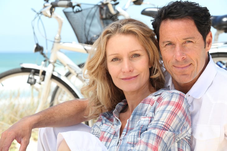 Happy couple in their 40s sitting by the beach