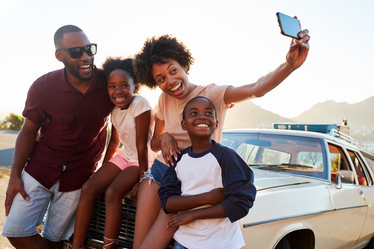 African American family taking selfie by car.