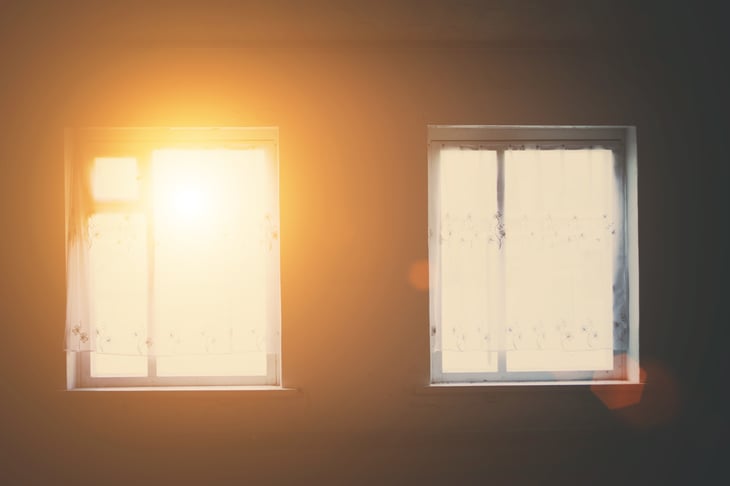Windows with light shining through into dark room