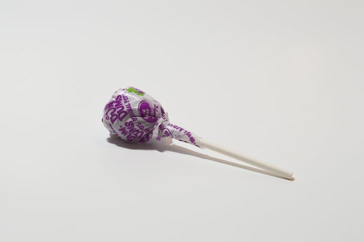 purple grape dum dum lollipop sucker white background