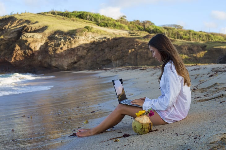Woman working on a laptop on a beach