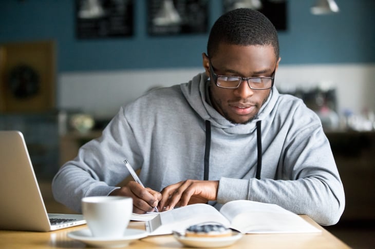 African American man writing at table.