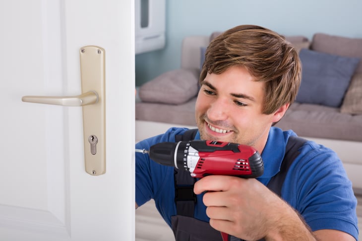 A handyman replaces a door lock
