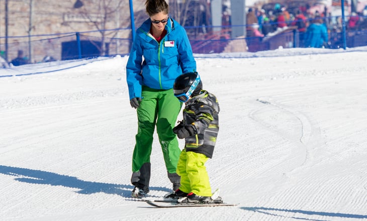 Ski instructor with a young child on the bunny slope