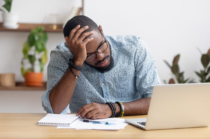 A frustrated man sits at his laptop computer