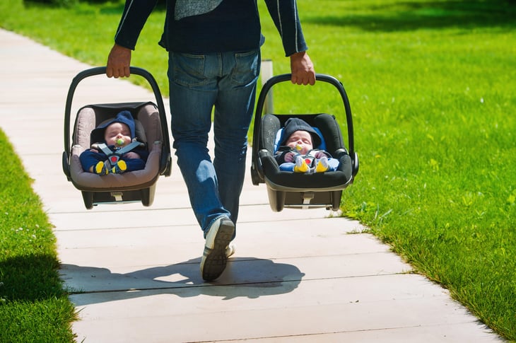 Father carrying baby twins