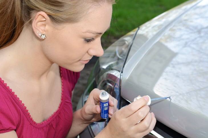 Woman repairs scratches and chips on car