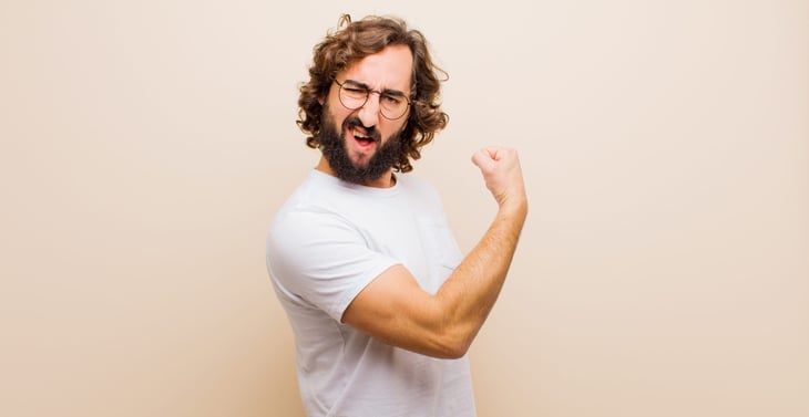 young bearded man in glasses flexing his bicep