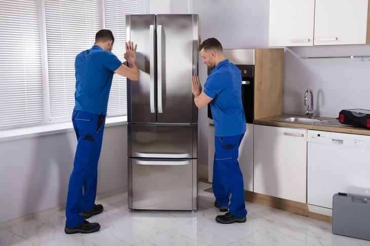 Movers install refrigerator