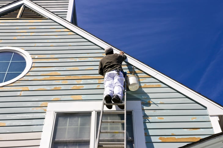 Person on ladder painting a house.