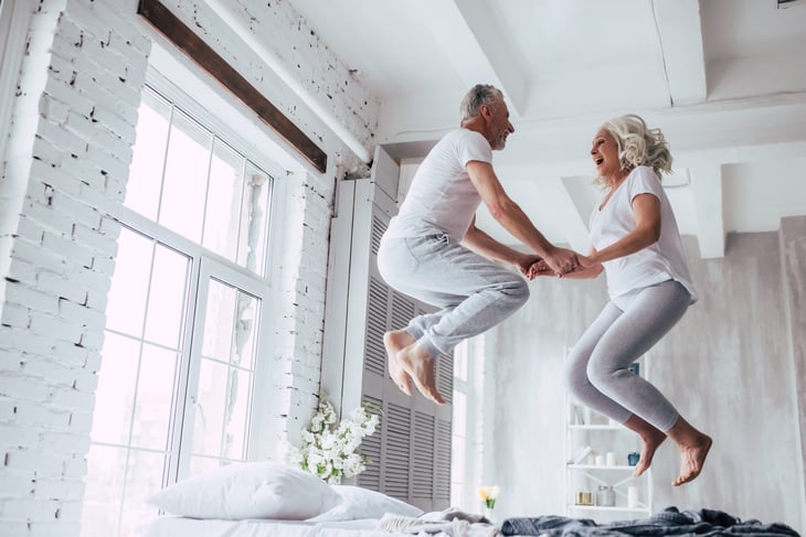 senior elder old man woman white couple jumping bed fun love
