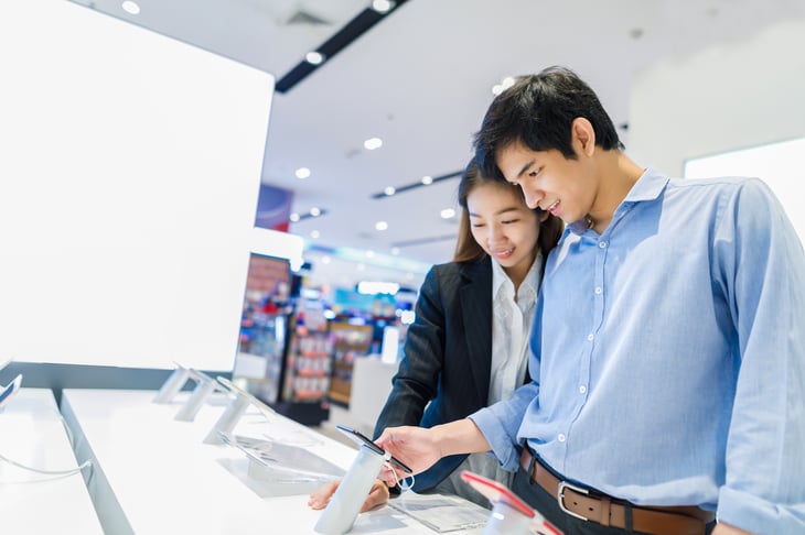 People looking at cellphones in store.