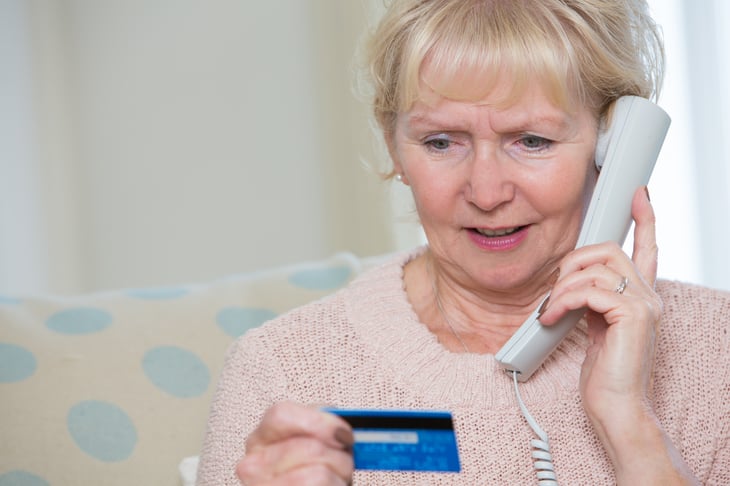 Woman on phone, looking at credit card
