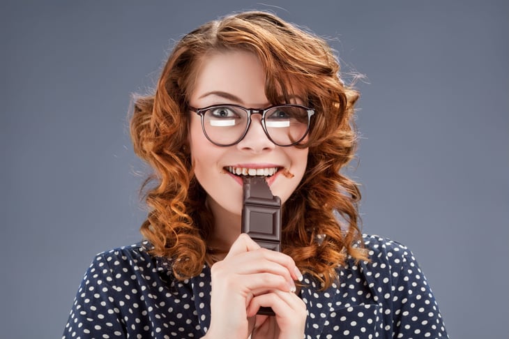 A woman eats a chocolate bar