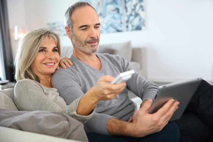 An older couple watches TV on the couch at home