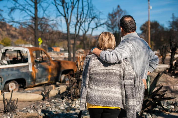 Couple looking at their home destroyed by a fire
