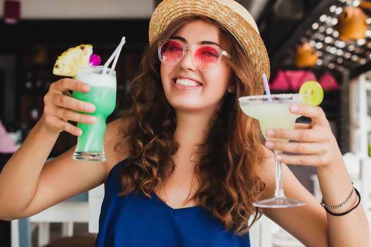 A woman holds up two cocktails